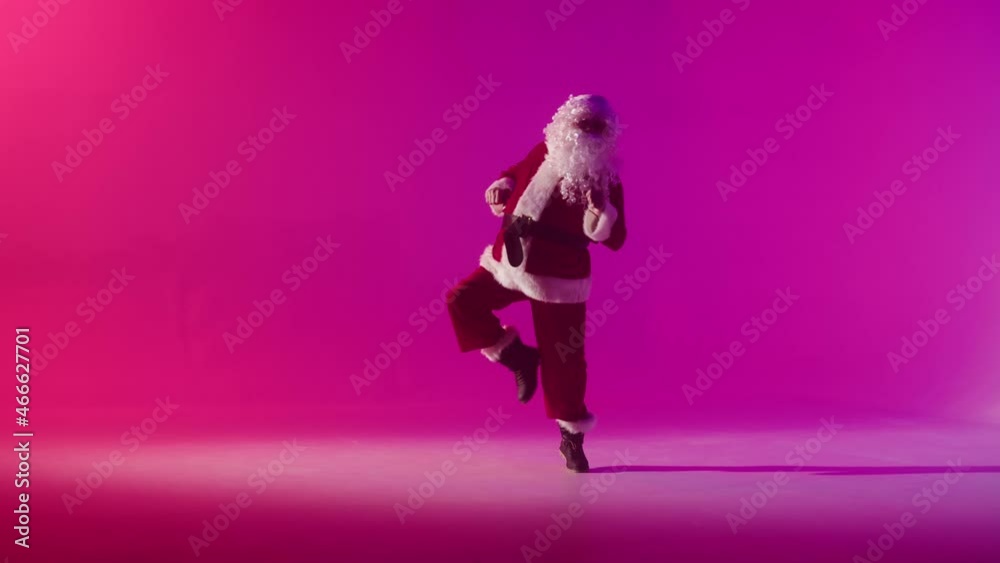 Santa Claus dancing on red background. Senior man in costume of Santa having fun in studio. New year party and christmas time, holidays concept. Santa Claus dancing on red background. Senior man in costume of Santa having fun in studio. New year party and christmas time, holidays concept.