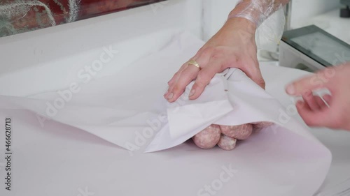 A butcher wrapping sausages in butchers paper. 