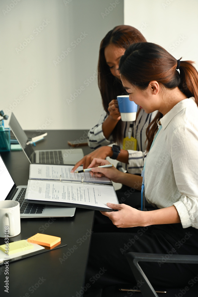 Two business people discussing financial data report together in office. Two business people discussing financial data report together in office.