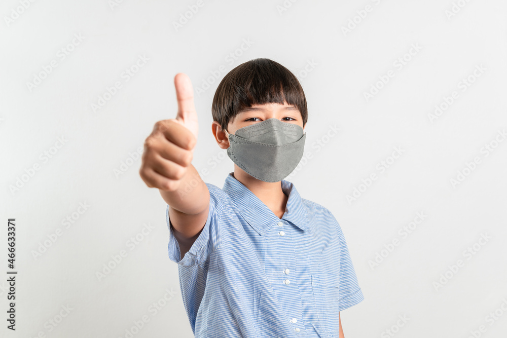 Happy Positive cute Mixed race kid boy wearing face mask showing thumbs up for good back to school due to the Coronavirus pandemic. Vaccination inoculation and healthy concept. White background space Happy Positive cute Mixed race kid boy wearing face mask showing thumbs up for good back to school due to the Coronavirus pandemic. Vaccination inoculation and healthy concept. White background space