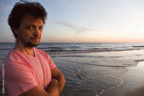 Retrato al atardecer en la playa de un hombre joven blanco vestido con colores claros. Pantalón de karate. photo