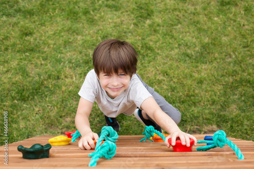 a smiling boy looks into the camera and plays on the playground