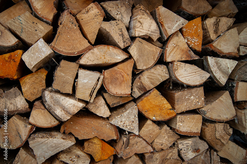 Dry oak firewood stacked in a pile, chopped wood for winter heating of the fireplace. Natural wood background.