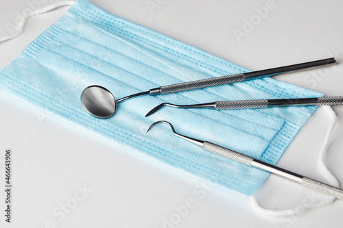 Dentist tools and medical mask on white background