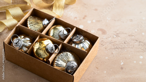 Different shape vintage Christmas balls into the box on beige background with ribbon. Merry Christmas concept.