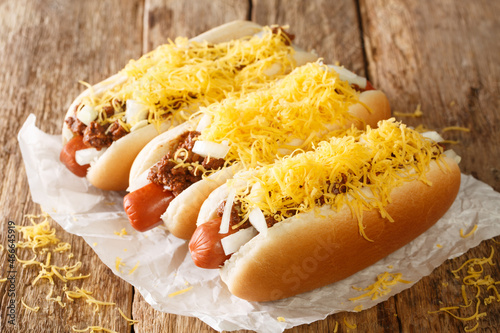 Obraz na płótnie American chili hot dog with beef sausage, cheddar cheese and onions close-up on an old wooden background. horizontal w salonie