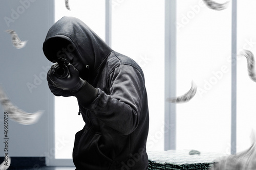 Fényképezés Criminal man in hidden mask pointing the shotgun while robbery the money