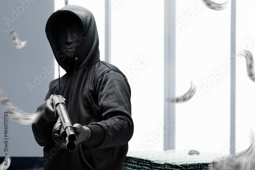 Criminal man in a hidden mask holding the shotgun while robbery the money photo