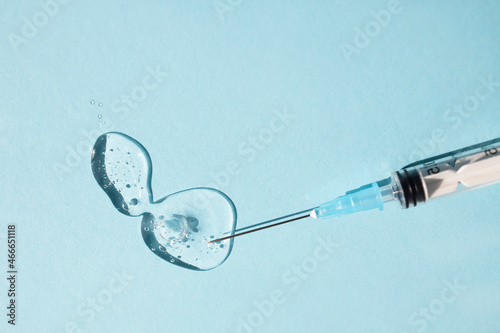 Disposable syringe with a transparent gel-like liquid on a blue background. Side view, place for text.
