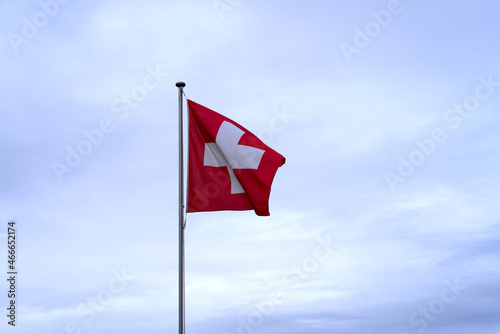Swiss flag blowing in the wind at Axalp at Bernese Highlands on a grey cloudy autumn day. Photo taken October 19th, 2021, Brienz, Switzerland.