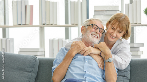 Caucasian old senior happy grandparents grey bearded hair husband and pretty wife sitting cuddling laughing together on sofa in living room at home watching comedy movie from laptop computer © Bangkok Click Studio