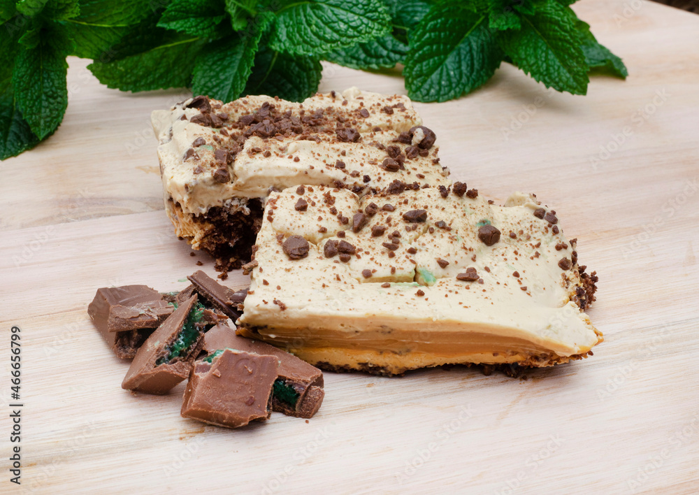  slices of Traditional South African Peppermint crisp tart or dessert on wooden surface garnished with fresh mint and pieces of peppermint chocolate - obrazy, fototapety, plakaty 