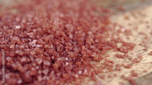 Red Hawaiian sea salt crystals falling in a heap on a wooden surface in slow motion. Macro. Mineral gourmet ingredient. Dolly shot photo