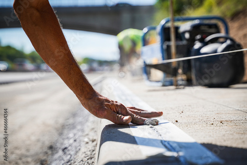 The road worker grouts the sidewalk and smoothing it with his finger.