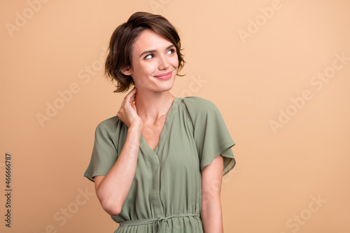 Photo of young dreamy happy woman look empty space hand neck smile idea isolated on beige color background
