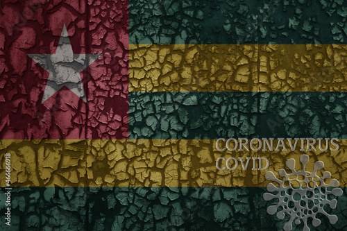 flag of togo on a old metal rusty cracked wall with text coronavirus, covid, and virus picture.