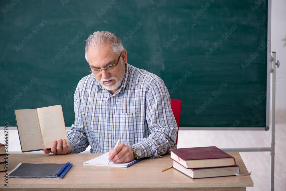 Old male teacher in the classroom Old male teacher in the classroom