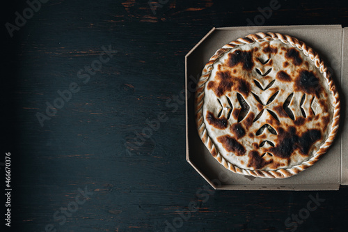 Ossetian beef pie in a box. Meat pie on a wooden background photo