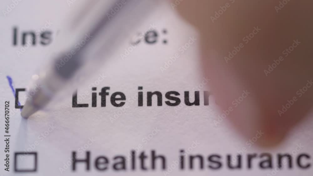 The person ticks off the life insurance item on the form. Close-up. Paperwork.