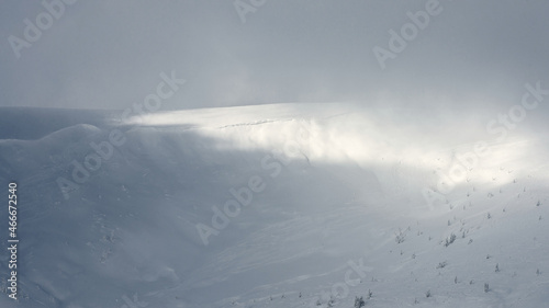 Ski slope between two mountain slopes. The mountain slope covered with snow. The cloud descends on the hillside.