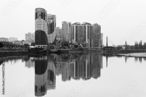 view of new modern multi-storey apartment buildings with reflection in the water of the Kuban river on a foggy autumn morning black and white photo