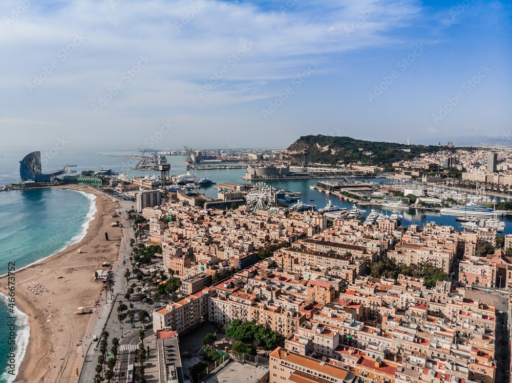 Drone shot Barcelona. Port with boats near the coast. Drone view of a vibrant swimming and sunbathing beach in Barcelona. People are relaxing on the beach. Panoramic view of the city of Barcelona.