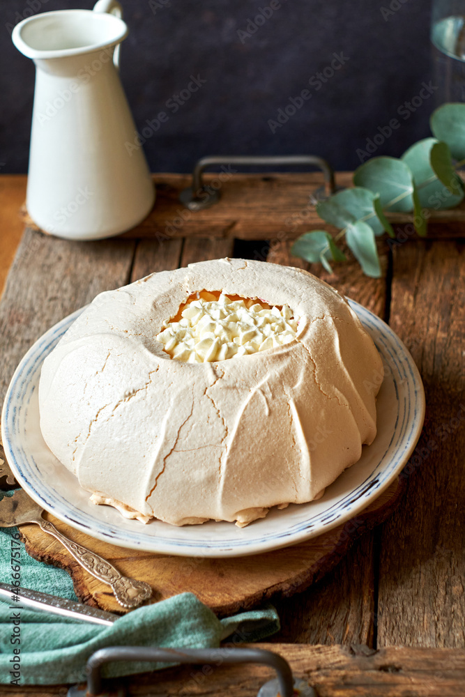 Pavlova cake on a white plate and a wooden board. Pavlova cake on a white plate and a wooden board.