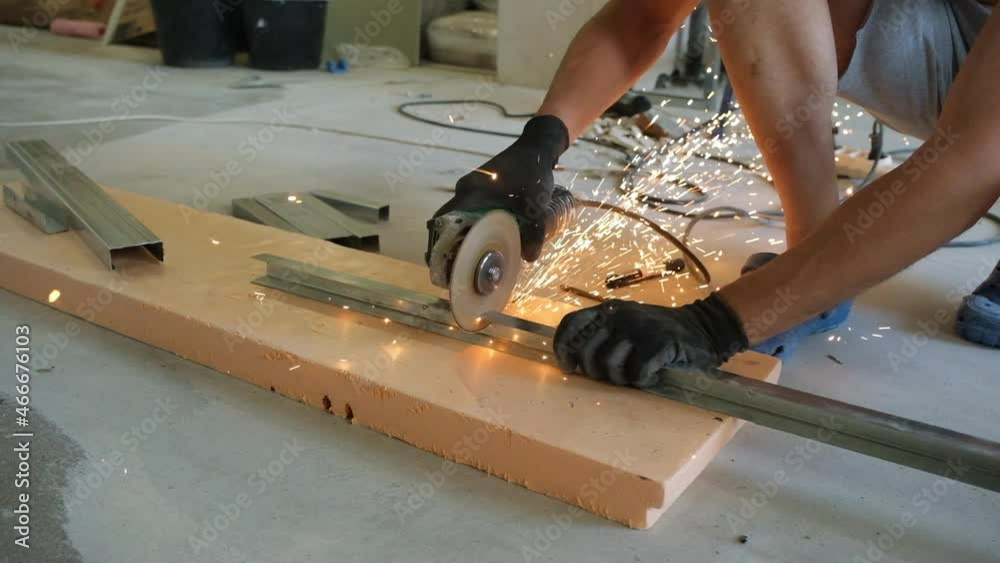 a man using a grinder cuts off a metal profile. close-up. Sparks fly away. Concept - DIY apartment renovation. a man using a grinder cuts off a metal profile. close-up. Sparks fly away. Concept - DIY apartment renovation.