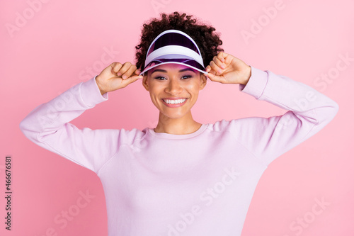 Portrait of young good looking smiling afro american sportive woman training wear visor isolated on pink color background