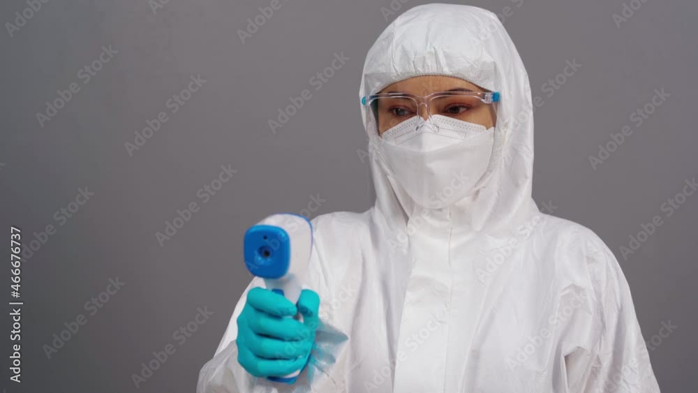 doctor in protective PPE suit scanning with infrared thermometer, IR Thermoscan doctor in protective PPE suit scanning with infrared thermometer, IR Thermoscan