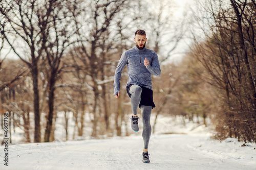Sportsman running in place in forest at snowy winter day. Winter fitness, healthy lifestyle, cold weather © dusanpetkovic1