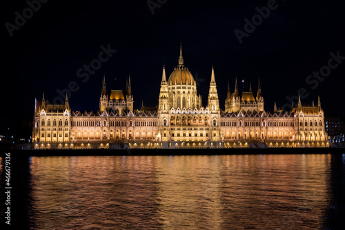 view of the facade of the building of the parliament of budapest hungary at sunset at night with lights on the banks of the Danube river © Sheviakova