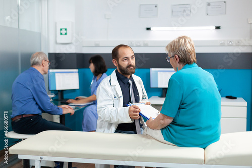 Old patient doing signature on checkup files for healthcare and treatment in medical office. Specialist talking to senior woman about osteopathy and physical rehabilitation for recovery