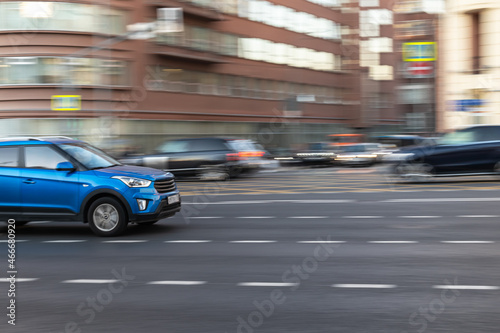 Fast moving blue car on a city street. Blurred motion. © Natalia
