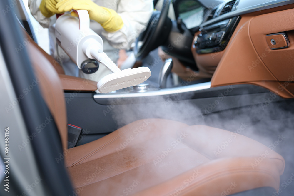 The specialist cleans the chair in the car with a washing vacuum cleaner  Stock Photo
