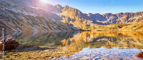 Autumnal Tatra mountains. Crystal water in the blue lake Big Pond surrounded by mountains in Valley of Five Lakes (Tatra National Park). Travel, ecology concepts. Poland. Europe. Selective focus.