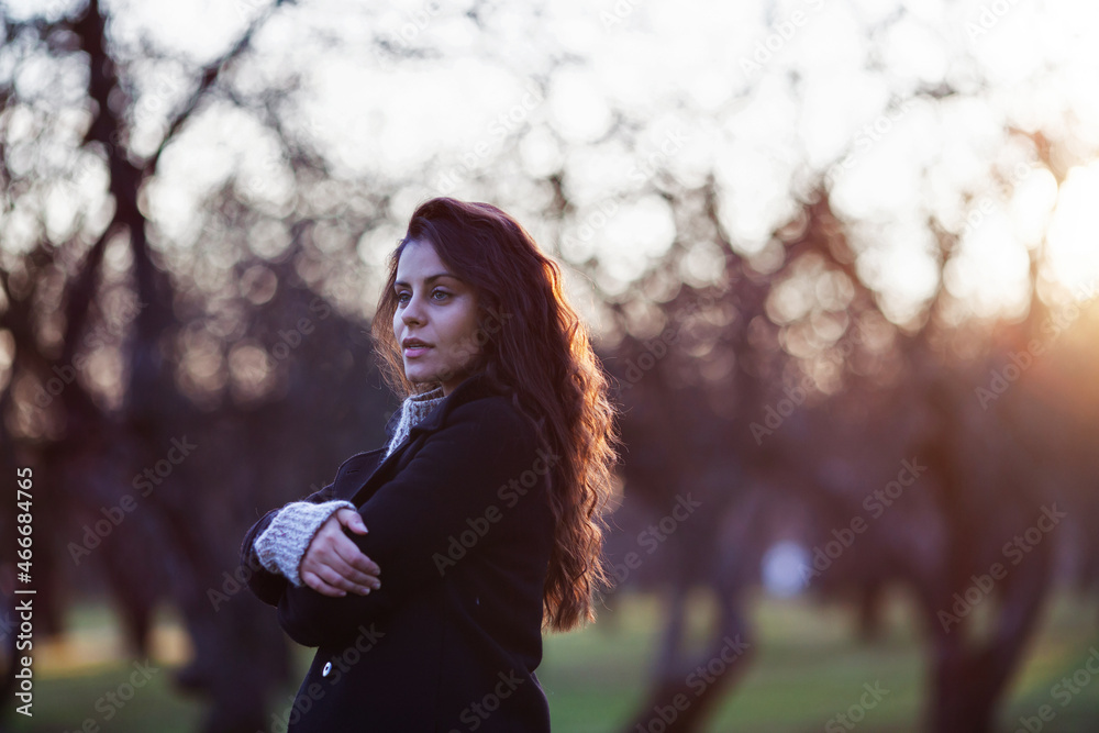 Young beautiful woman in a coat stands in an autumn park in the evening Young beautiful woman in a coat stands in an autumn park in the evening