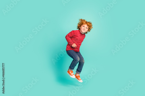 Full body photo of funny little boy jump wear shirt jeans sneakers isolated on blue background