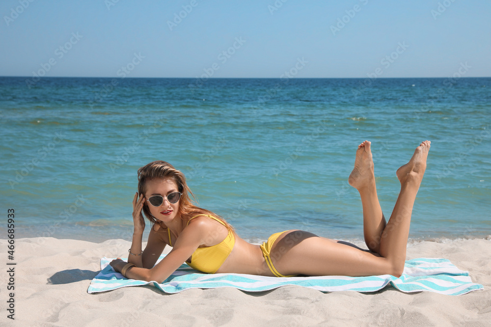 Beautiful woman with beach towel on sand near sea