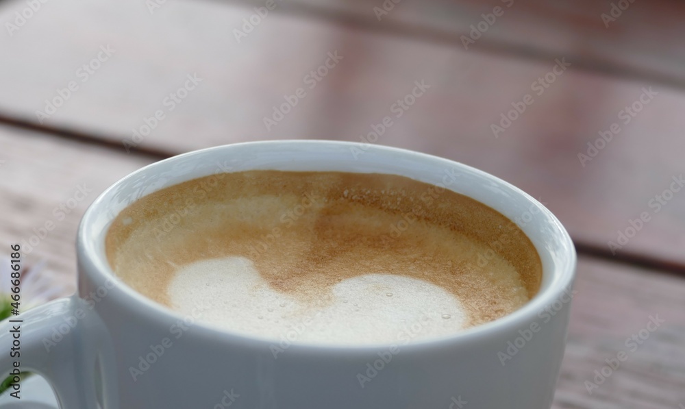 Coffee with creamy foam and white cup on wooden table Coffee with creamy foam and white cup on wooden table
