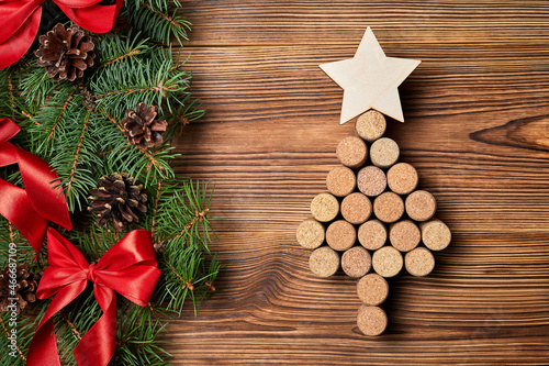 Christmas tree from wine corks with a star on top on a wooden background with fir branches, cones and bows