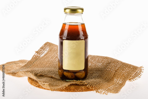 Health benefit herb of dry Malva nut on kitchen plate and extract drink with ginkgo and longan mix in glass bottle with editorial brand label as nourishment and detox beverage photo