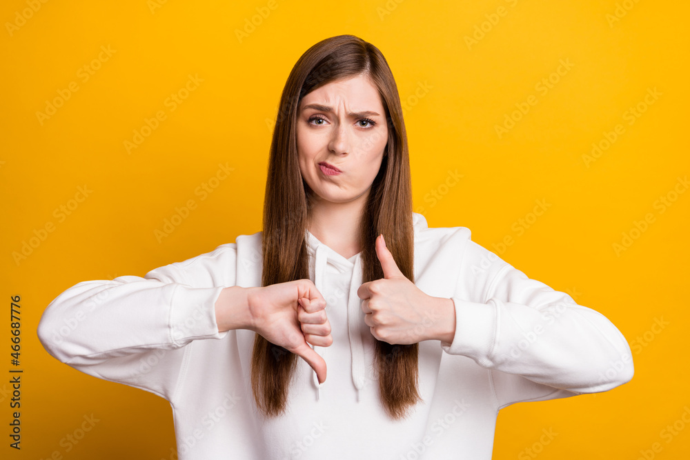 Photo of unhappy young upset doubtful woman make thumb up down decide isolated on yellow color background Photo of unhappy young upset doubtful woman make thumb up down decide isolated on yellow color background