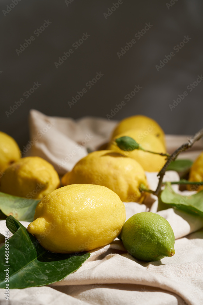 lemon with leaves composition on a wooden table with a beige tablecloth on a sunny day.