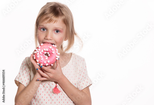 Happy little girl eat donut isolated on white. Blond child with glazed ring doughnut. Happy childrens day and sweet life. Free space for text