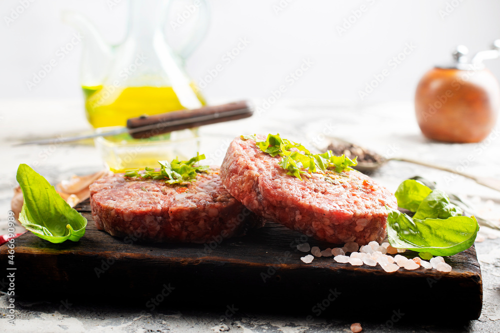 Raw cutlet of minced meat on a wooden cutting board.