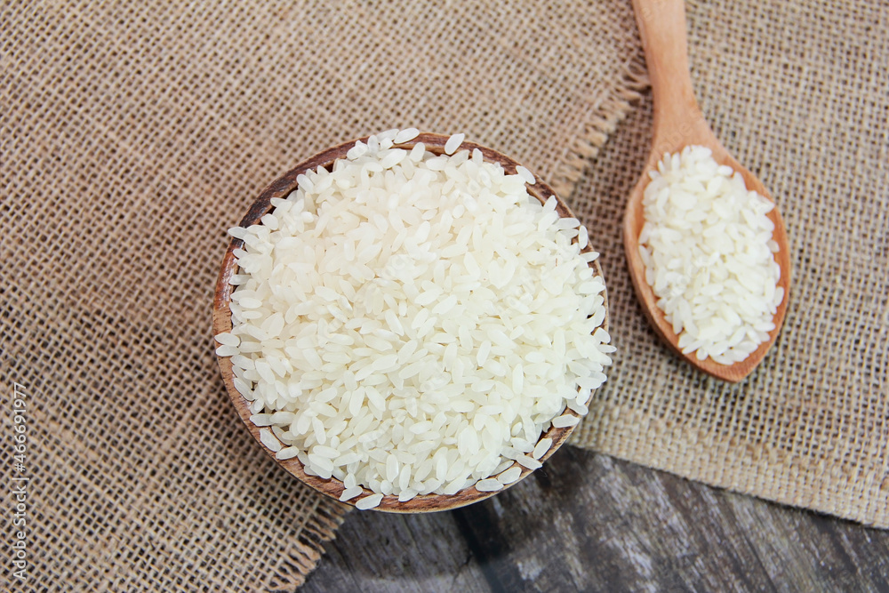 grains of white rice in a wooden spoon and plate grains of white rice in a wooden spoon and plate