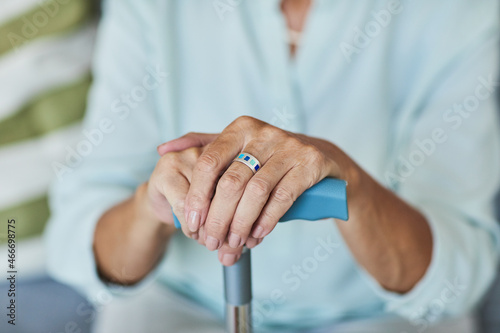 Close up of unrecognizable senior woman holding cane, focus on elegant hands with ring, copy space