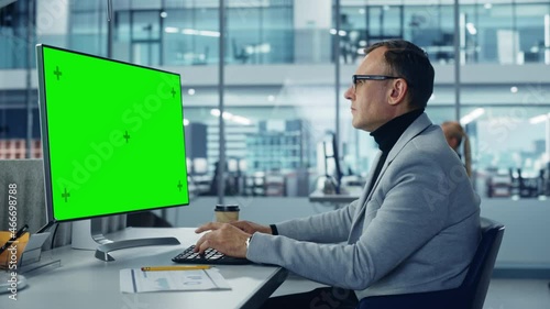 Diverse Corporate Office: Stylish Handsome Big Data Engineer Using Desktop Computer with Green Chroma Key Screen. Businessman Working on e-Commerce Project Marketing, Development. Static Medium Shot