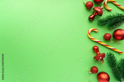 Christmas flat lay. Holiday decorations, lollipops cane and fir branches on green background, space for text